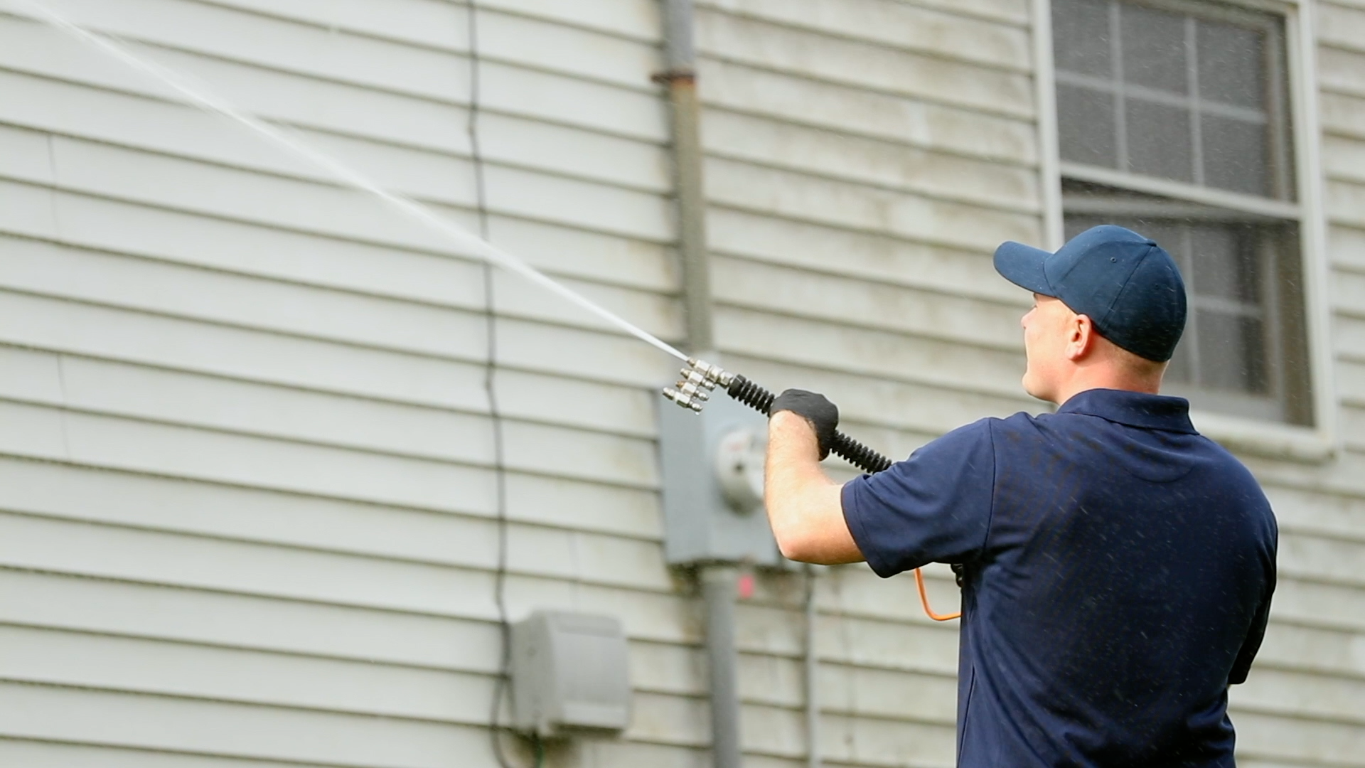 professional washing white siding of home